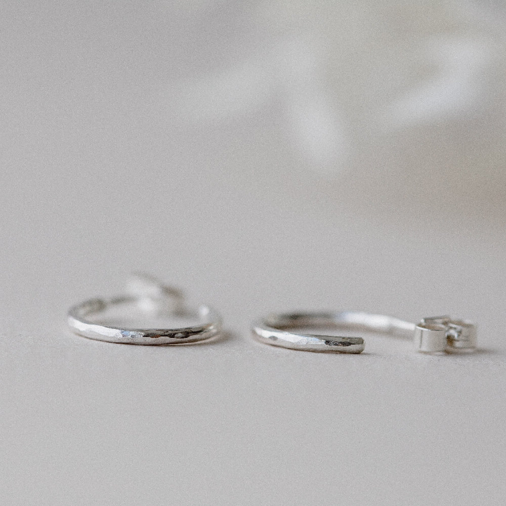 Hammered Silver hoop Earrings laying flat on a white background