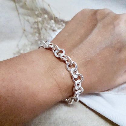A chunky hammered link silver bracelet being worn around a wrist 