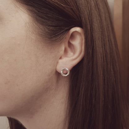 sterling silver hammered circle stud earring being worn in the ear of a lady with long dark hair