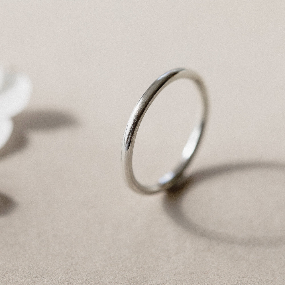 A simple silver infinity ring placed on a beige background.