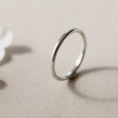 A simple silver infinity ring placed on a beige background.
